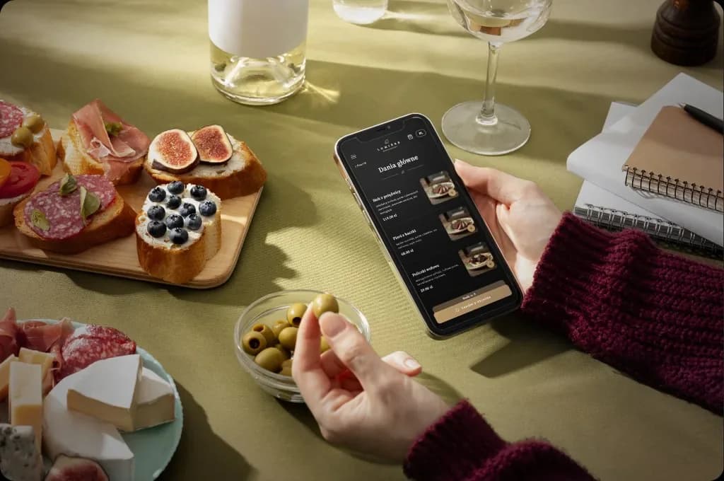 Gość przy stoliku z telefonem i otwartym menu QR