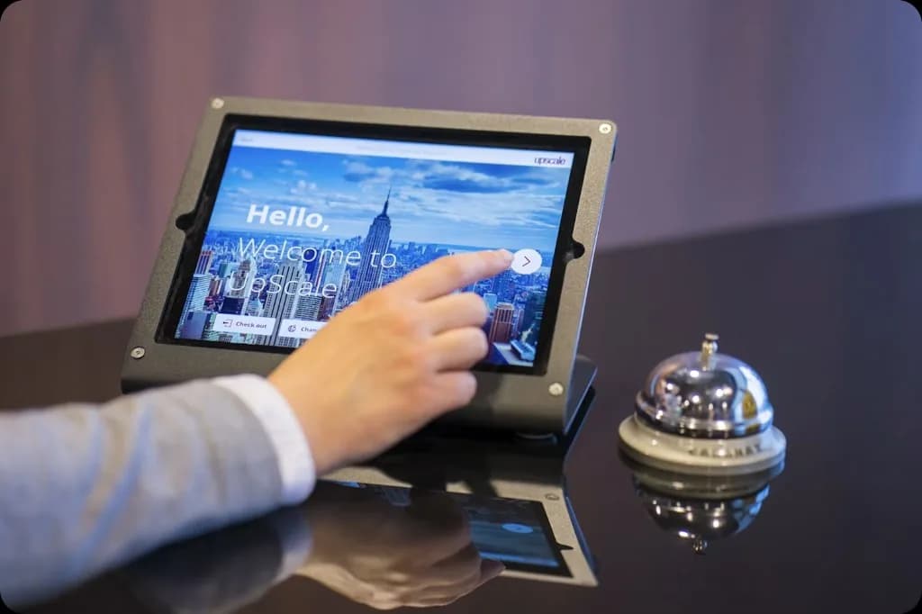 Tablet przy recepcji obok dzwonka, gość potwierdza wybór na ekranie